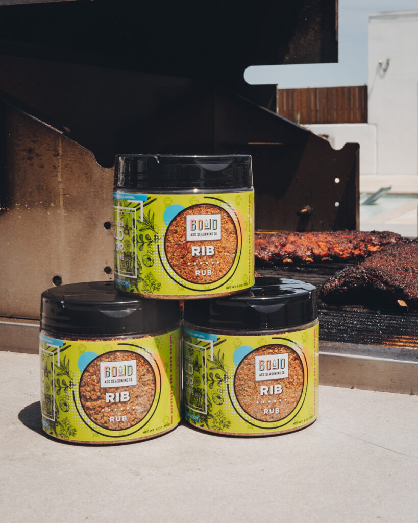 Bould seasoning in front of a grill with ribs