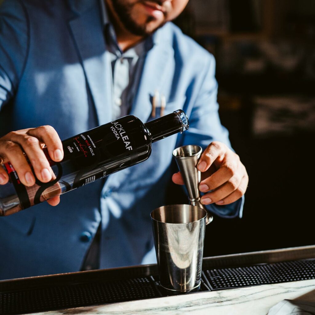 a man pouring a shot of Black leaf premium vodka