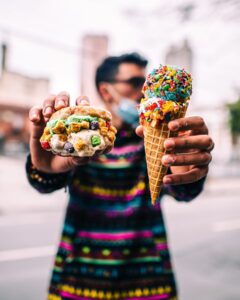 A Man holds an ice cream donut sandwich and a cone from Sweet Stacks in Atlanta