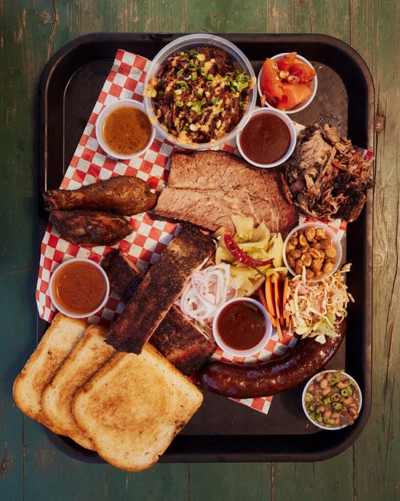 Distant Relatives Barbecue plate with texas toast, ribs, brisket, sausages, cole slaw, and beans
